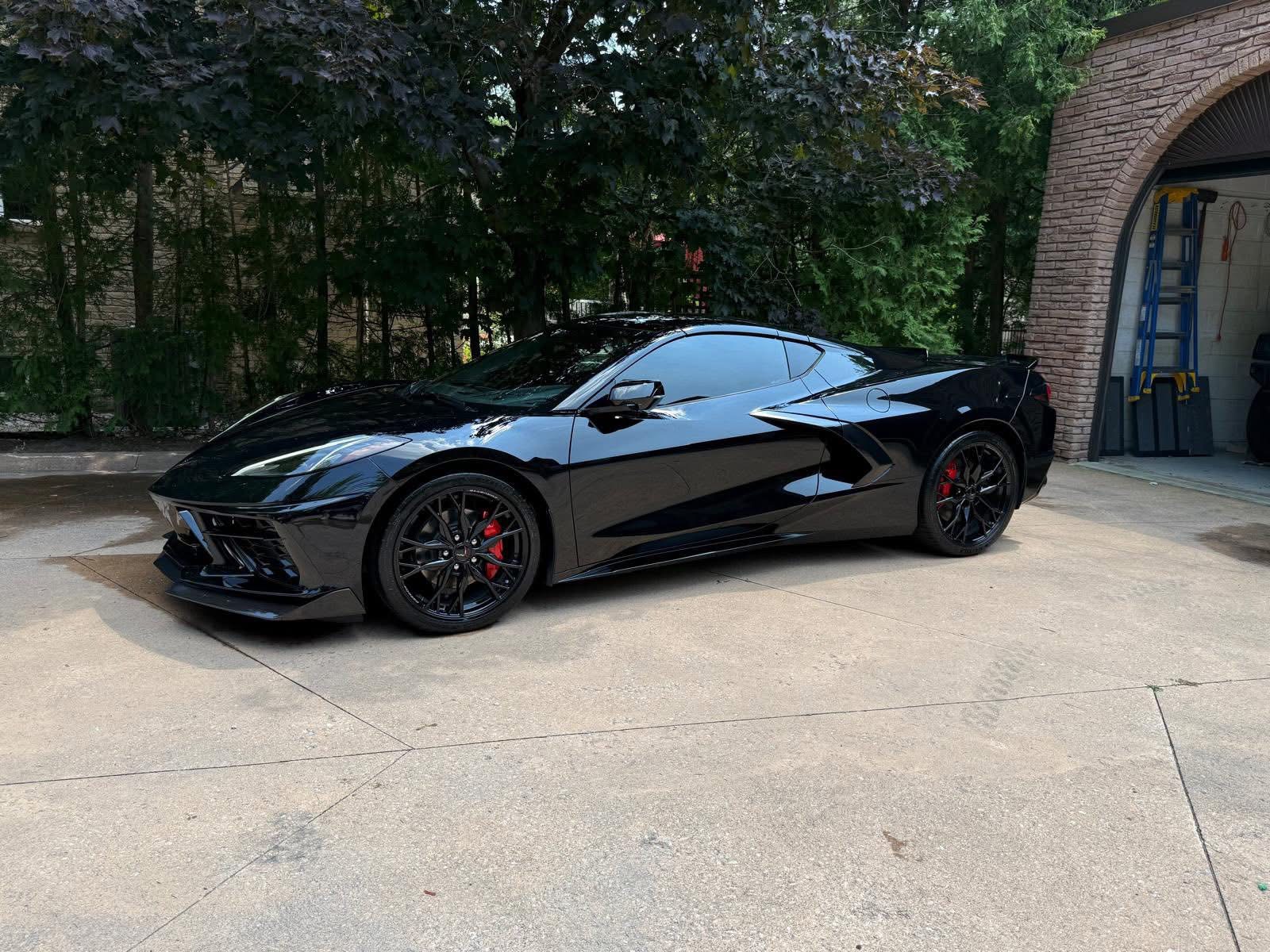 Full exterior detail finish, black sports car on driveway
